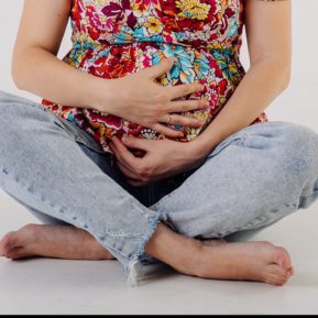 Pregnant women sitting crosslegged with her hands over her bump
