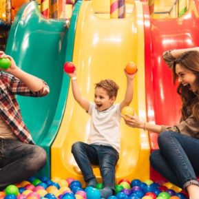 Parents enjoying playing soft play with their child.