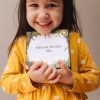 Smiling child holding her set of Enchanting Learning Cards