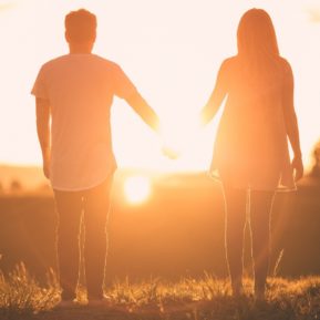 couple holding hands looking at sunset