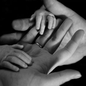 black and white close up of adult and baby hands