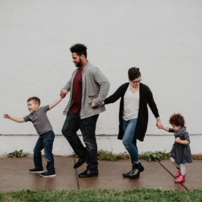 Two adults and two children holding hands and walking in a line