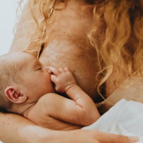 A mother with long hair breastfeeding her newborn