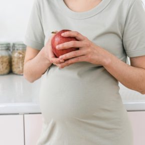 Pregnant women holding an apple over her bump