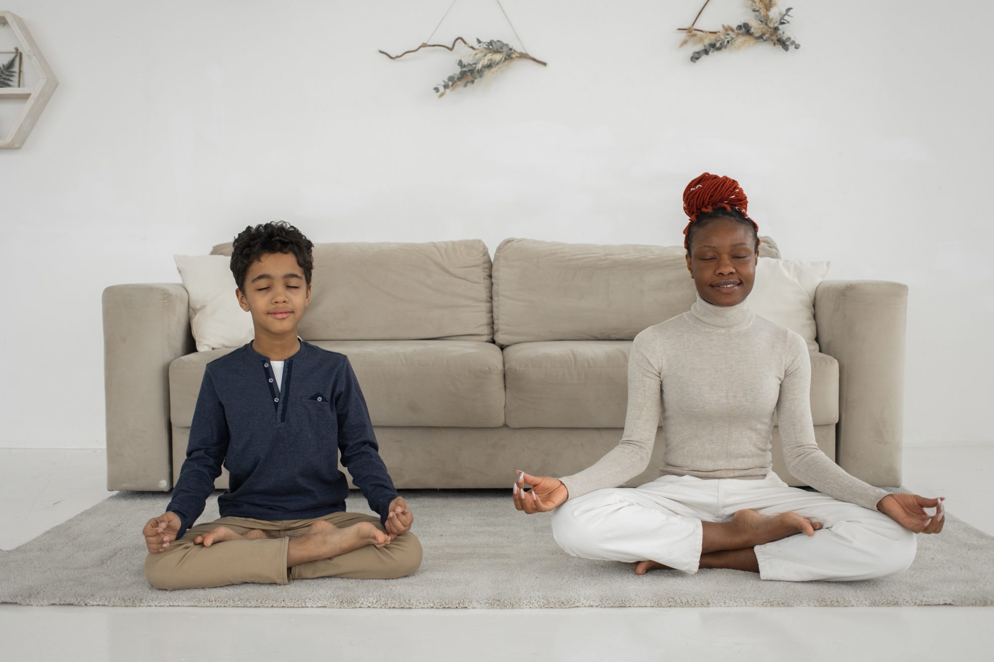 Boy and woman meditating in front of a sofa