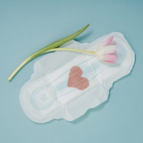 sanitary towel with a red heart shape next to a flower
