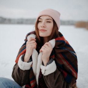 Woman holding her jacket collar in front of a winter background