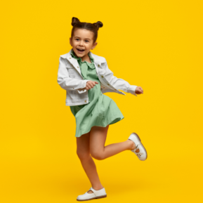 Young child dancing against a yellow background