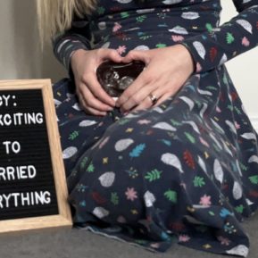 pregnant woman with her hands over her bump next to a sign