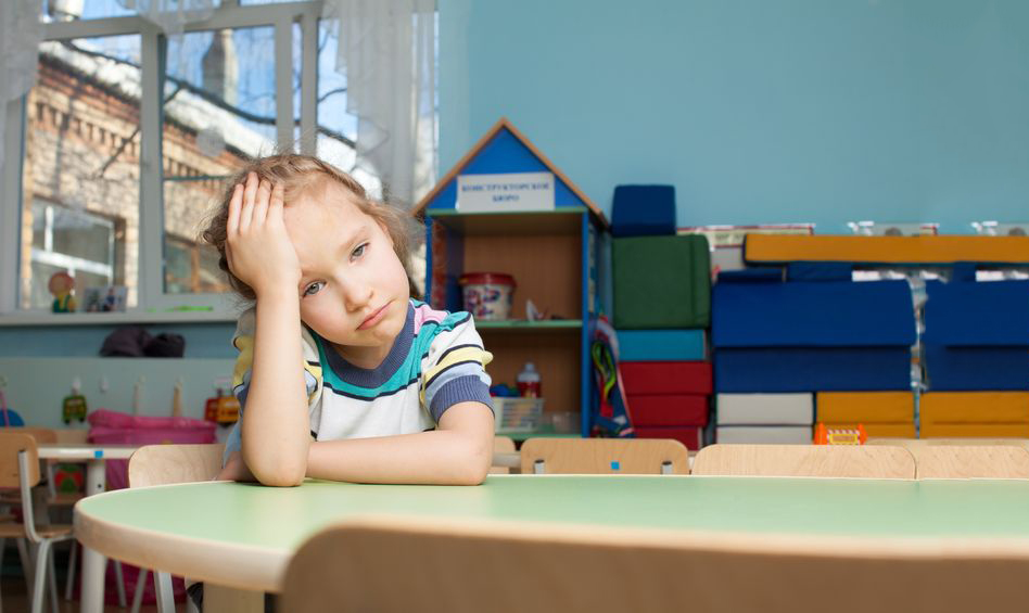 Child sat alone in classroom looking sad
