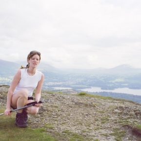 Woman crouching on a hill in front of a high up view