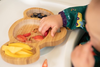 Young child's hand picking from a plate of food