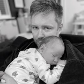 Man holding sleeping newborn baby
