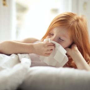 Child blowing nose on tissue