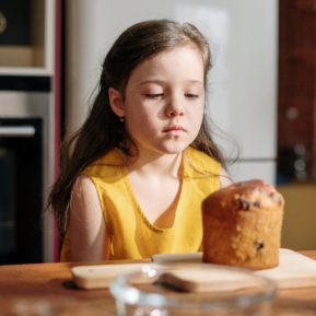 child sat in front of cake looking sad