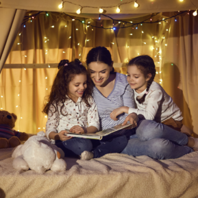 woman reading to two children in a den