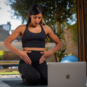 woman kneeling in front of laptop in workout gear