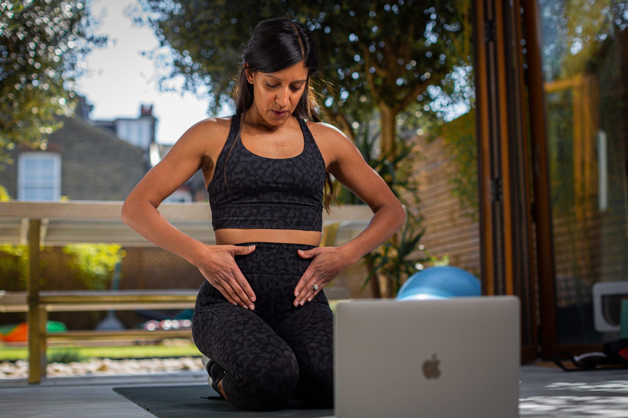 woman kneeling in front of laptop in workout gear