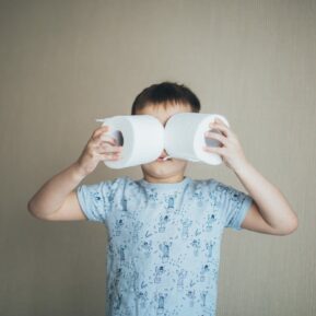 Boy holding toilet rolls in front of his face