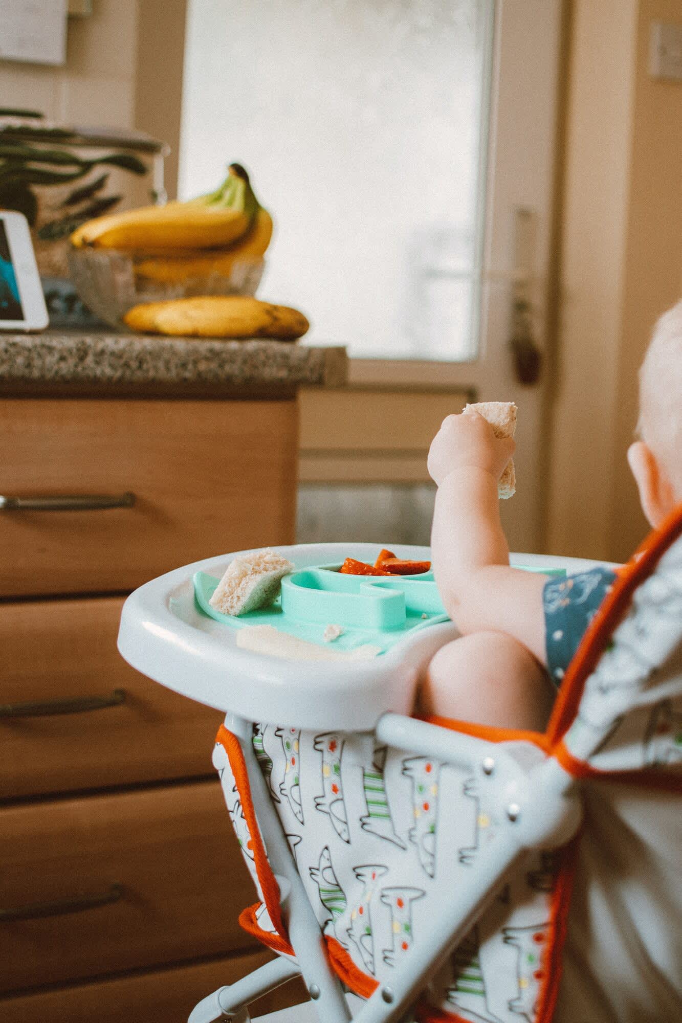 baby eating food from highchair