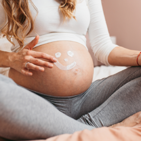 Pregnant woman putting cream on her tummy.